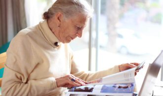 an elderly woman reads a magazine in assisted living